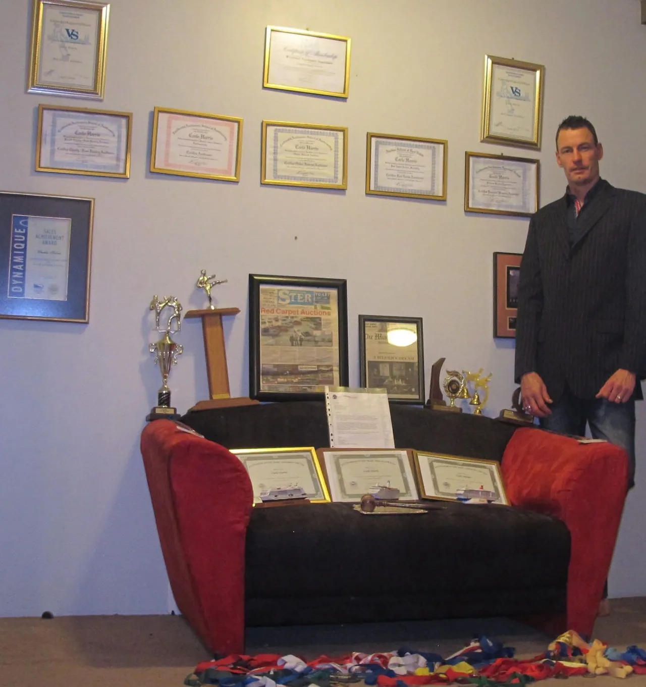 Carlo Harris with a display of professional certificates, trophies and auction press coverage